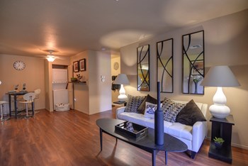 Living Room with Wood Inspired Floor, White Sofa, Black Table, Washer/Dryer and Large Decorative Black Bottle